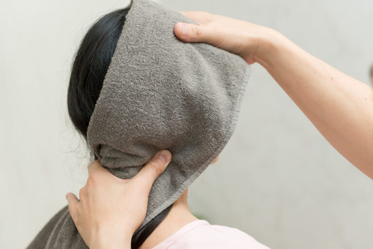 首から肩にかけての筋肉に手を当て、硬さを確かめながらゆるめている様子